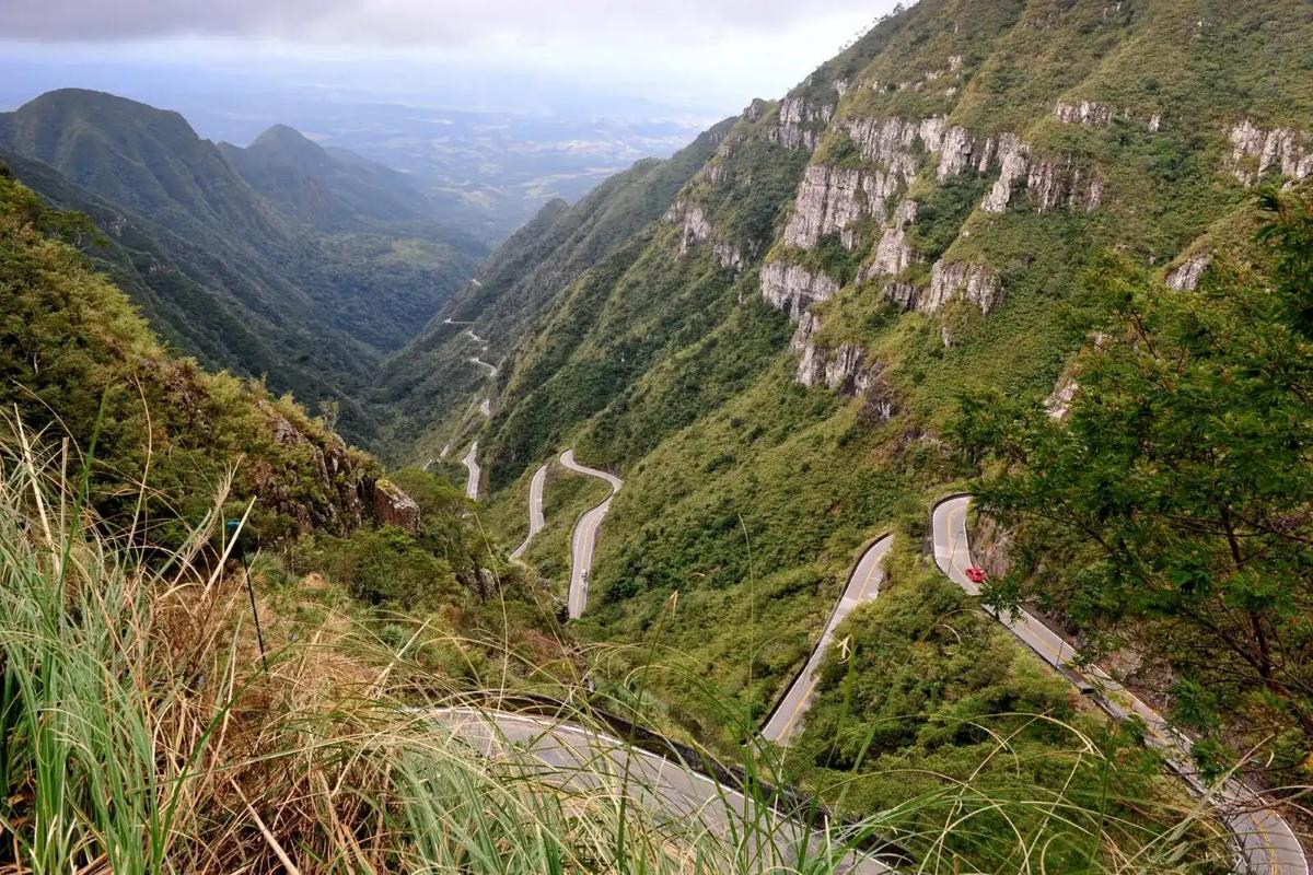Estrada em curvas descendo a serra entre montanhas verdes