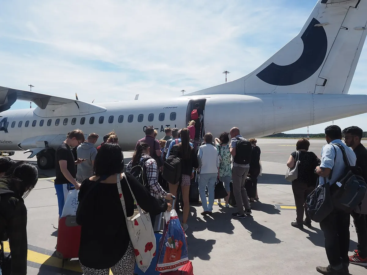 Passageiros na pista entrando no avião pela escada