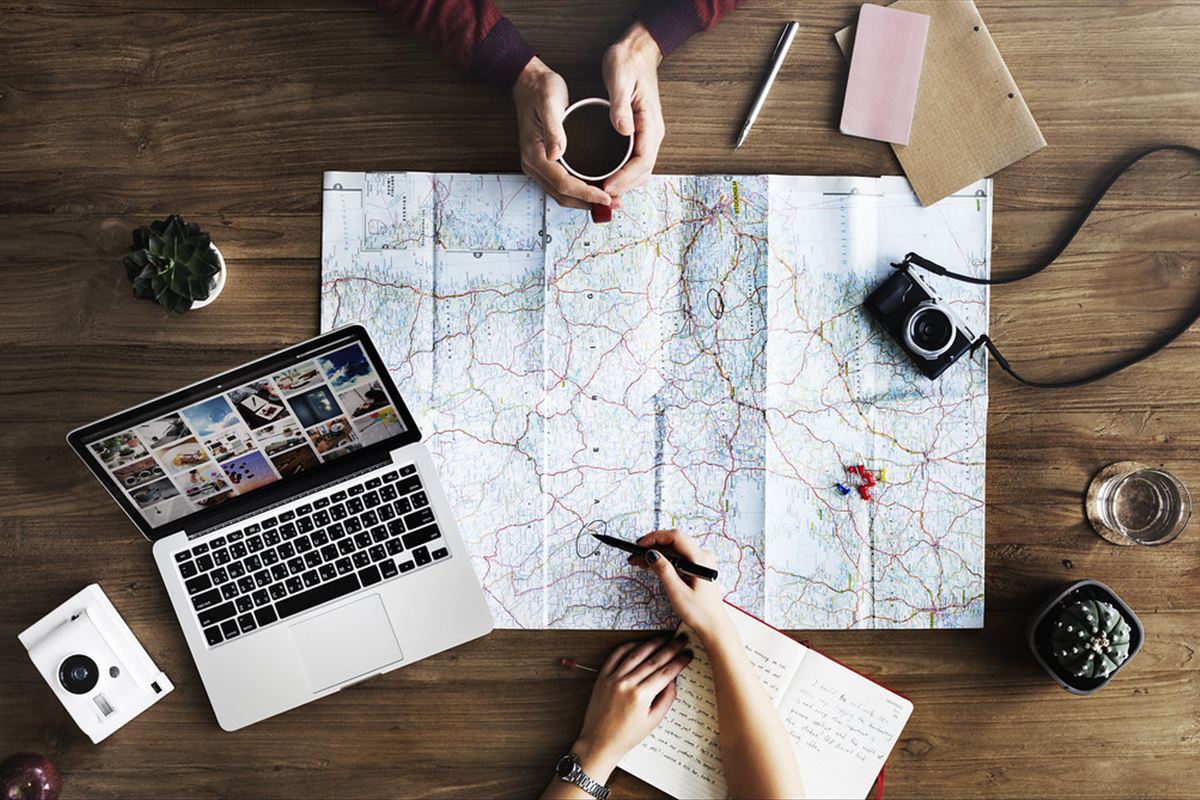Planejamento de viagem com mapa, notebook e celular